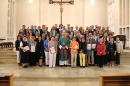 Ein große Gruppe von Frauen und Männern stehen im Altarraum der Klosterkirche in Esthal.