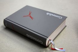 Man sieht ein Buch mit grauem Einband und einem roten Kreuzsymbol